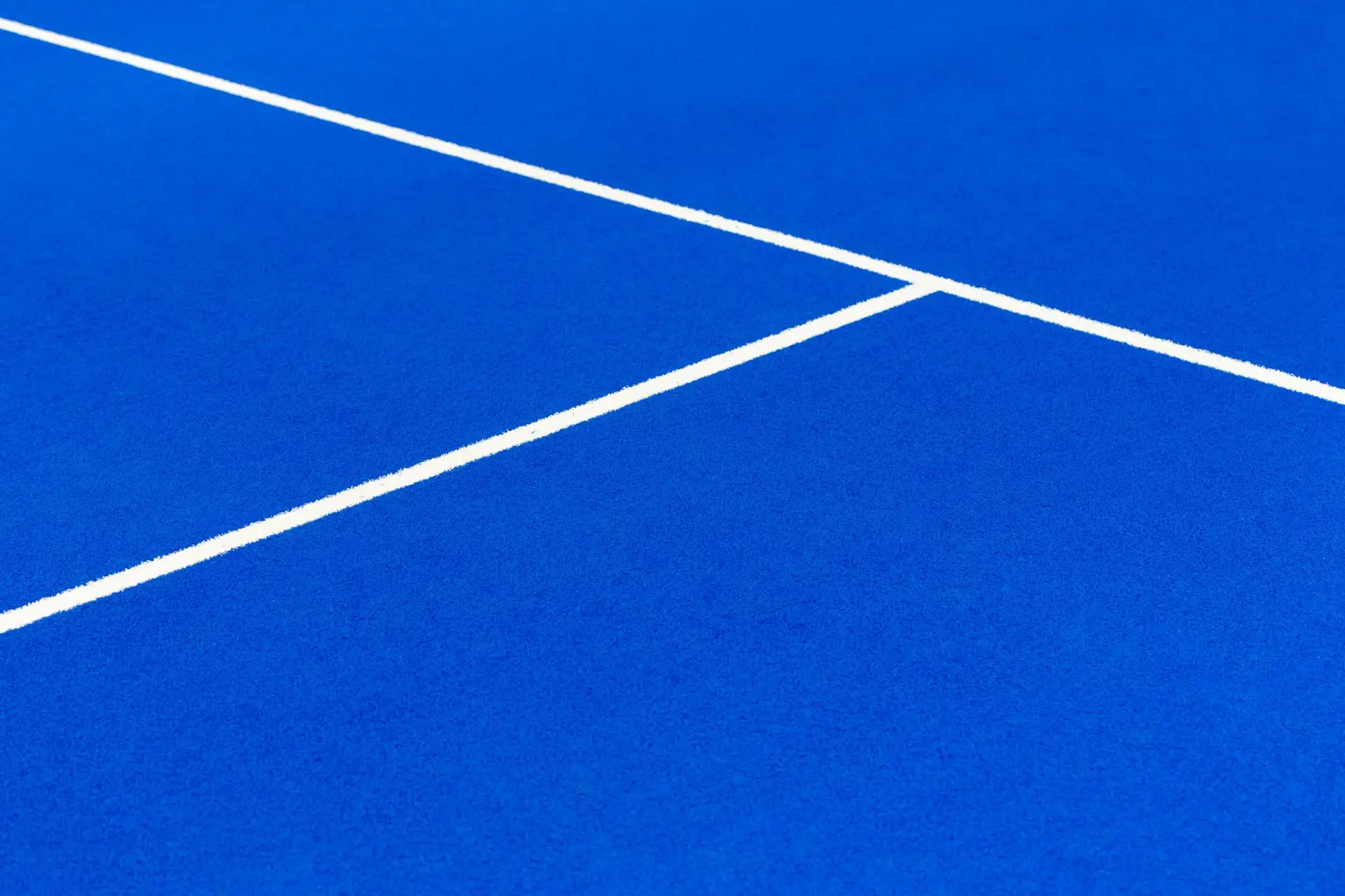 Close up of Blue padel court surface showing white lines