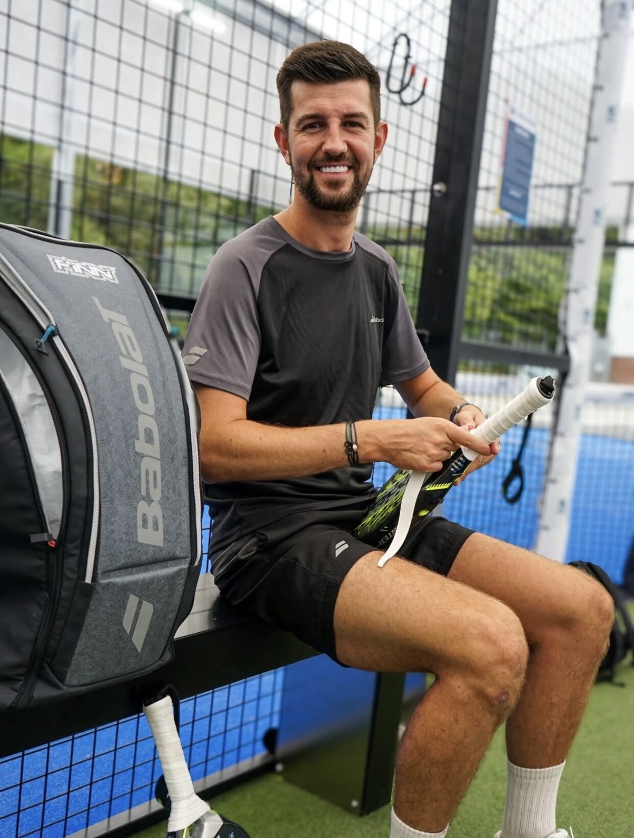 Liam Finn on bench outside padel court