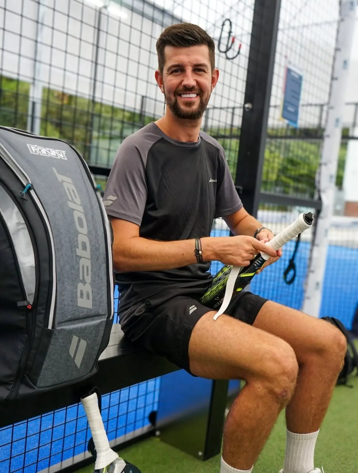Liam Finn on bench outside padel court