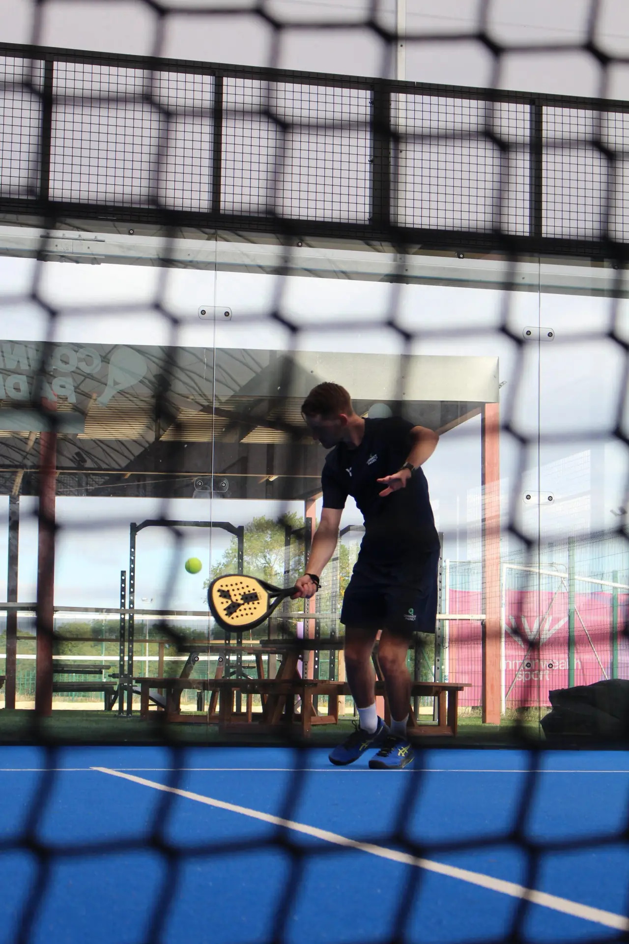 Harry Blundell on padel court hitting a ball