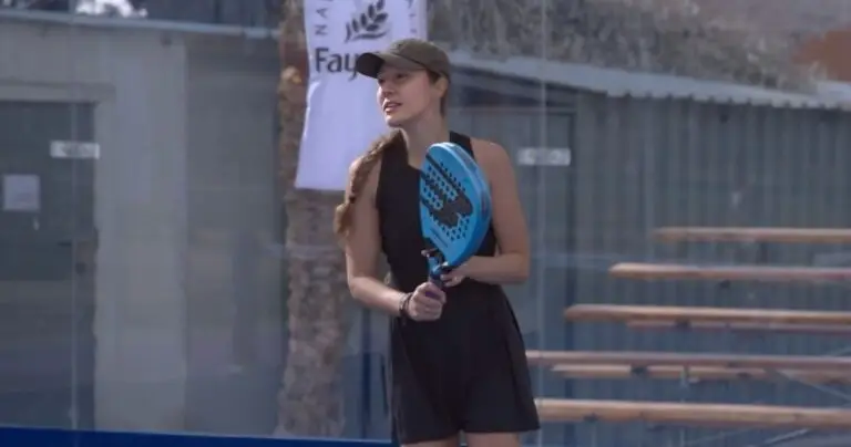 Anna Guryanova at the net during a tournament match, holding a blue padel racket