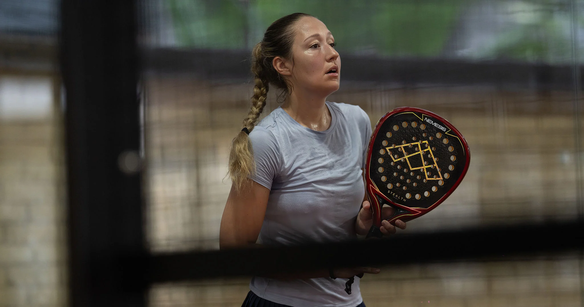 Anna Guryanova holding her padel racket between points at an indoor tournament