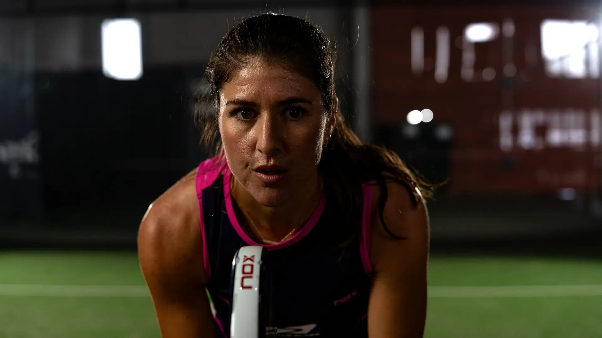 Brittany Dubins in the ready position, eyes on the camera, on an indoor padel court