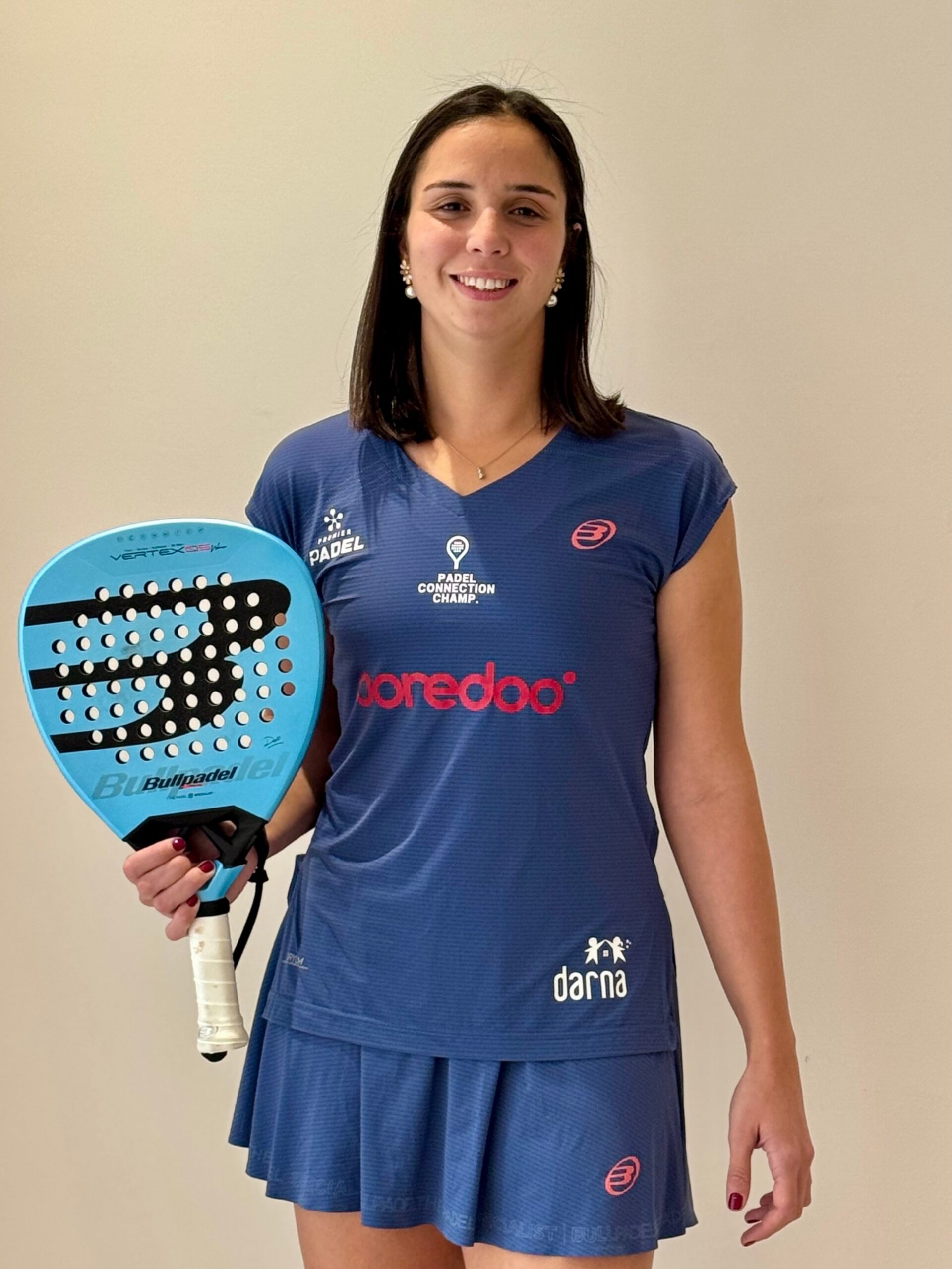 Dora Chamli in her blue Bullpadel and Ooredoo kit, holding a Bullpadel Vertex racket