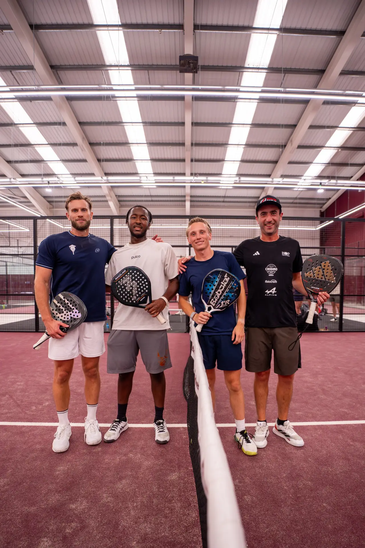 Four padel players at the net on an indoor court