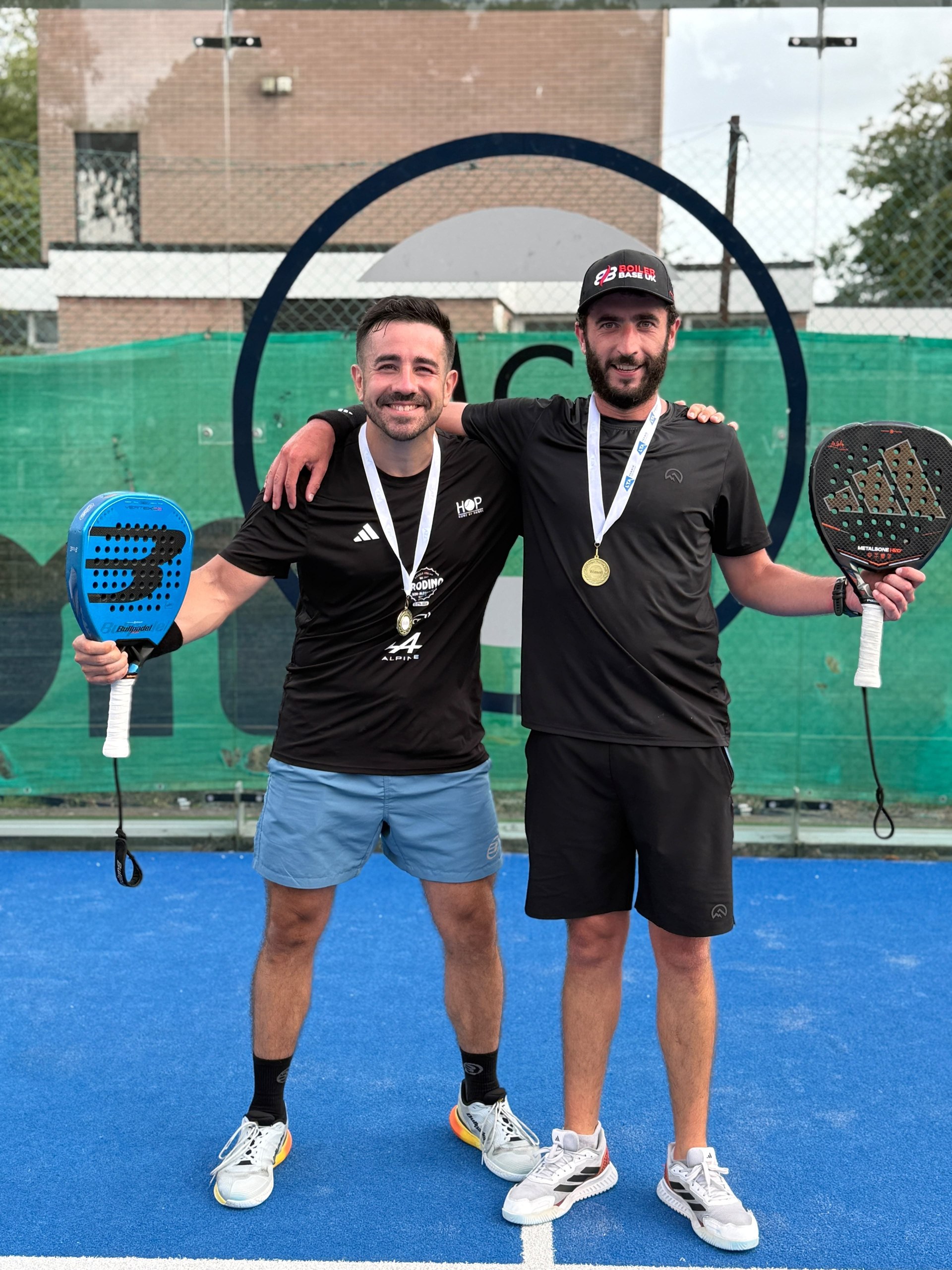 Jamie Guest and his doubles partner with tournament medals and padel rackets