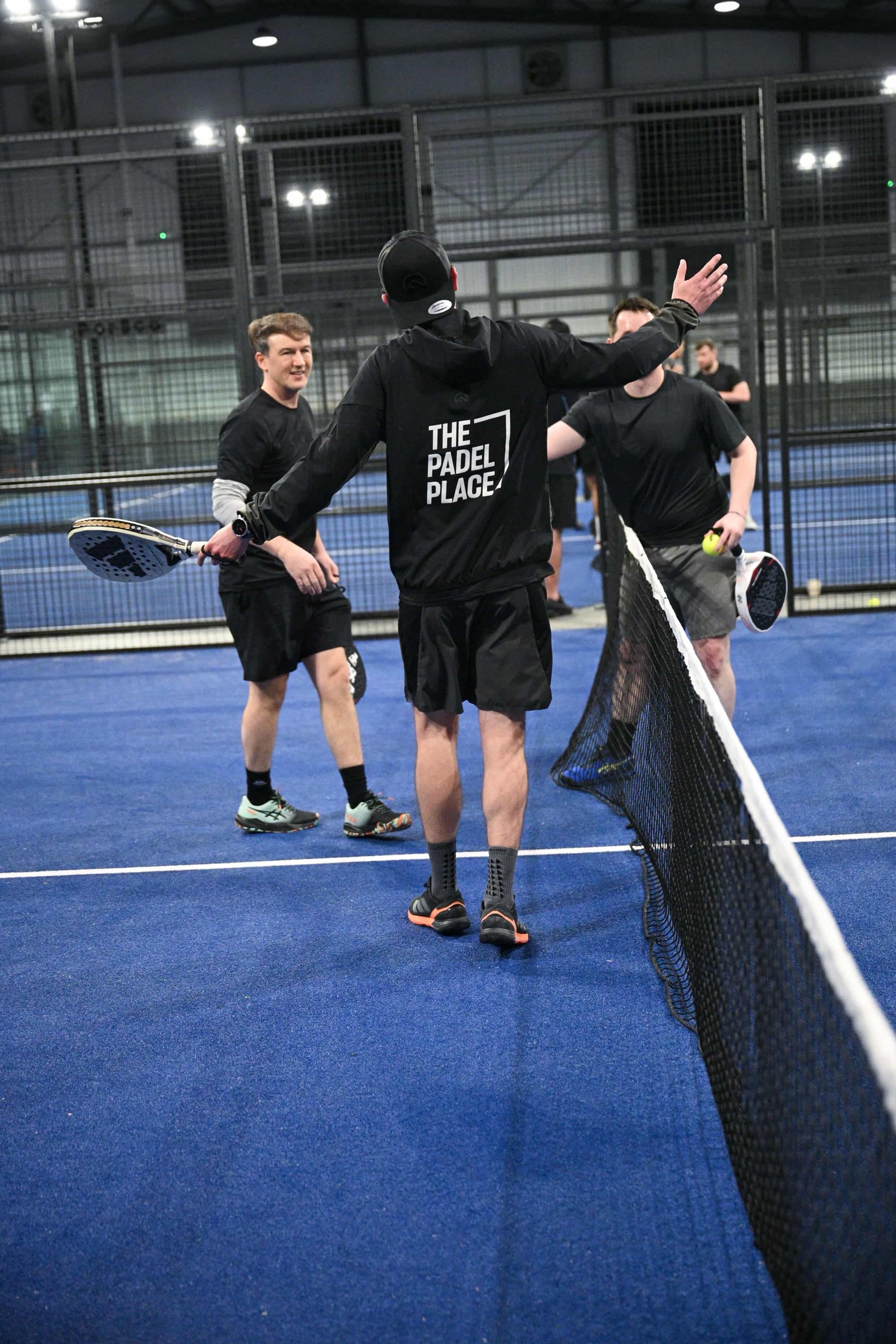 Players celebrating at the net after a padel match at The Padel Place