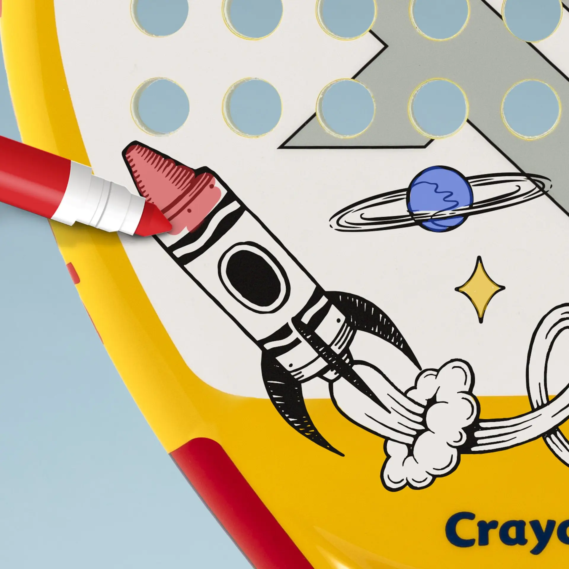 A red marker colouring in a crayon-shaped rocket drawn on the face of the yellow Raquex x Crayola racket